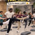 Une classe de fitness joyeuse s'échauffe ensemble avec des mouvements dynamiques.